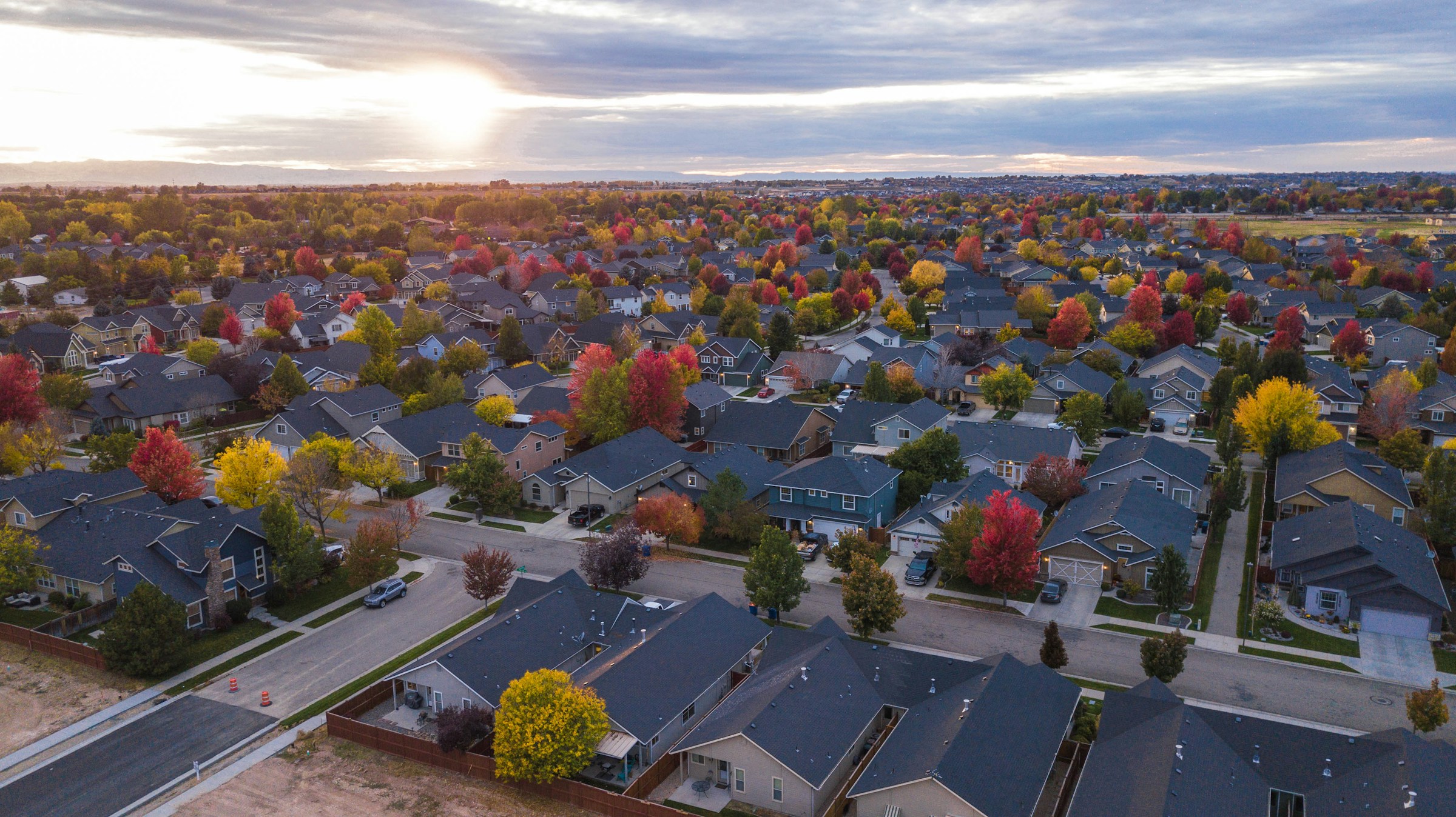An aerial view of suburban rooftops stretching to the horizon at dusk